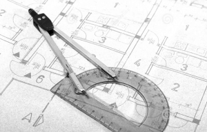 A compass and protractor placed on architecture blueprint drawing