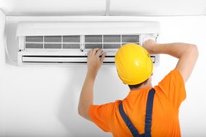 A technician repairs a wall mounted air conditioning unit
